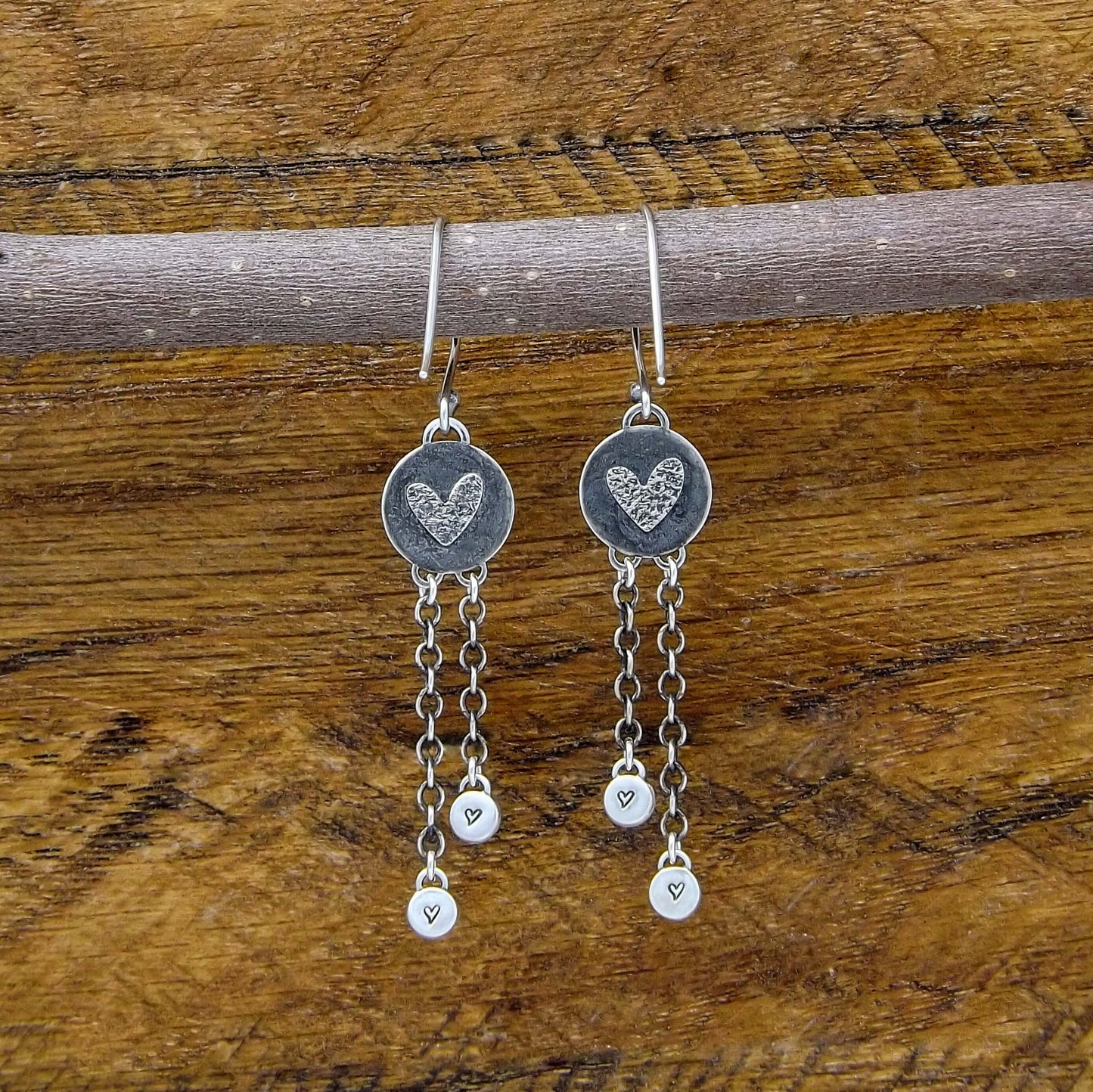Back view of a pair of sterling silver dangle earrings with heart designs adorning the back.