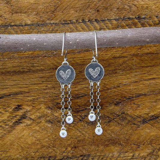 Back view of a pair of sterling silver dangle earrings with heart designs adorning the back.