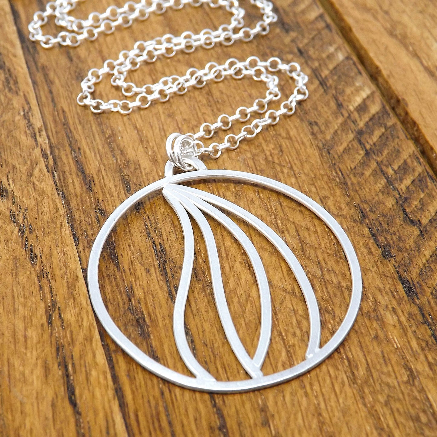 Left angle view of an argentium silver fire element necklace with a sterling silver rolo style chain.