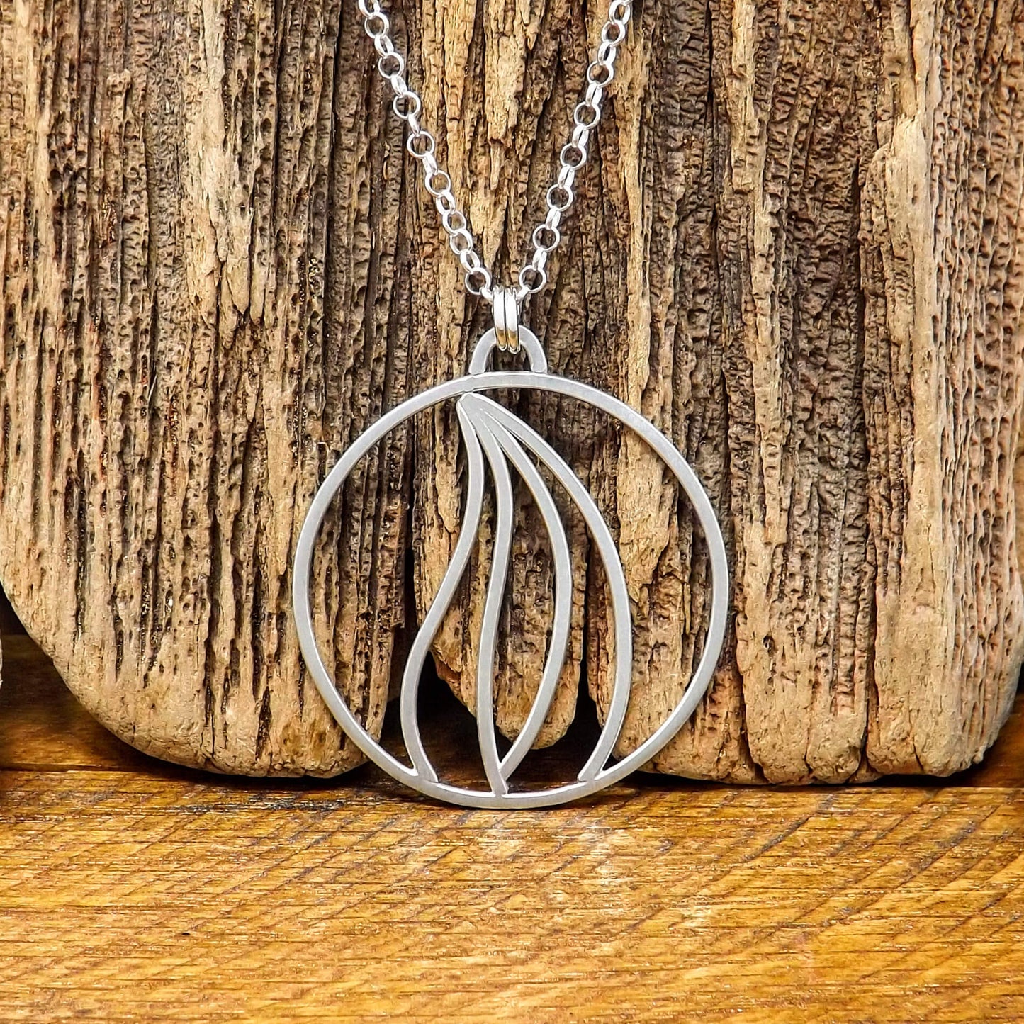 Close up front view of an argentium silver fire element necklace with a sterling silver rolo style chain.