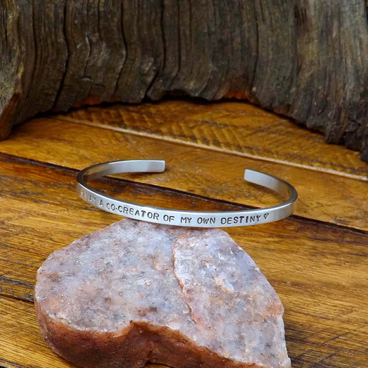 Right side view of a sterling silver affirmation cuff bracelet hand-stamped with "I AM A CO-CREATOR OF MY OWN DESTINY".
