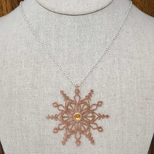 Display bust view of a copper snowflake necklace featuring a rose cut faceted citrine gemstone set in a fine silver bezel. Paired with a sterling silver chain.