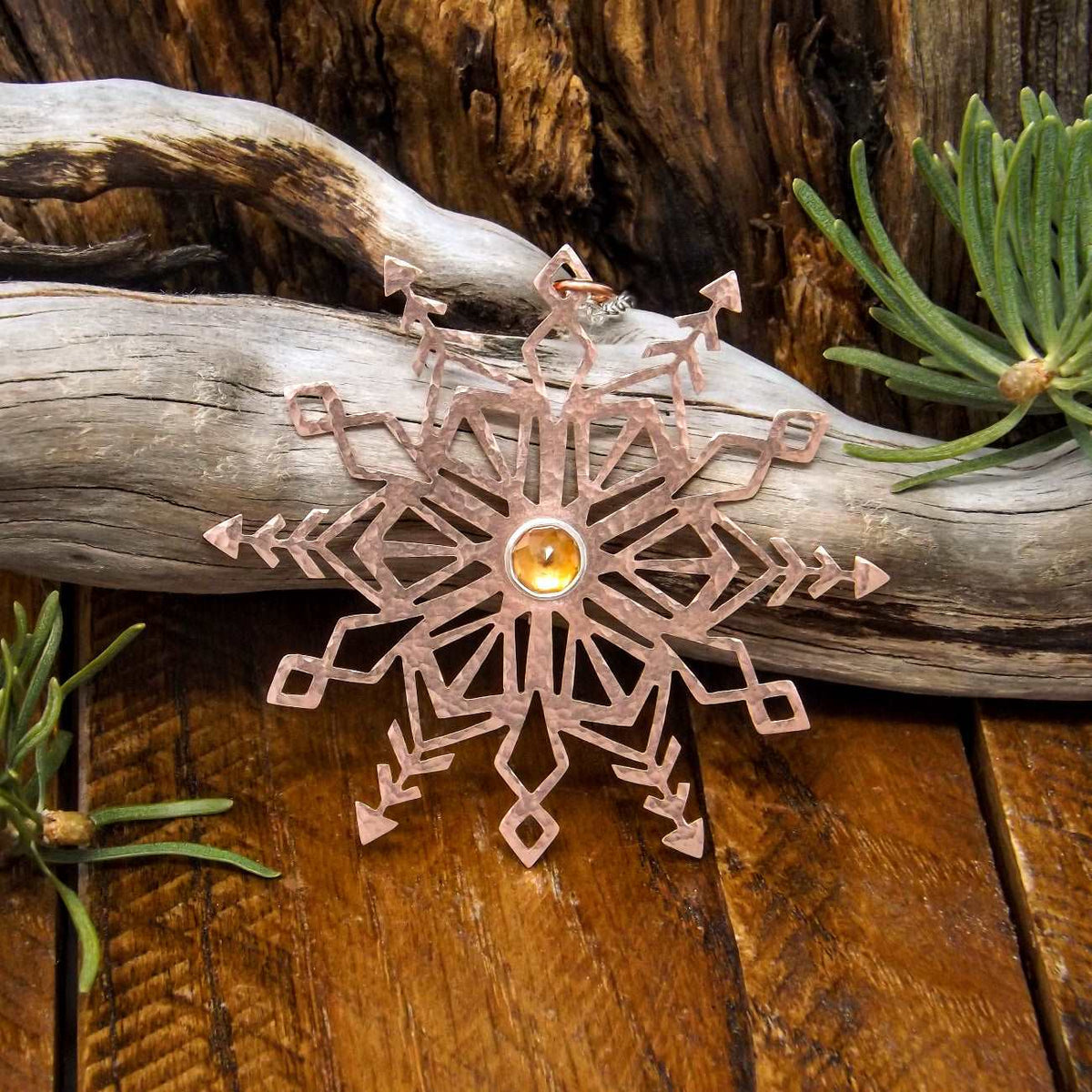 Front view of a copper snowflake necklace featuring a rose cut faceted citrine gemstone set in a fine silver bezel.