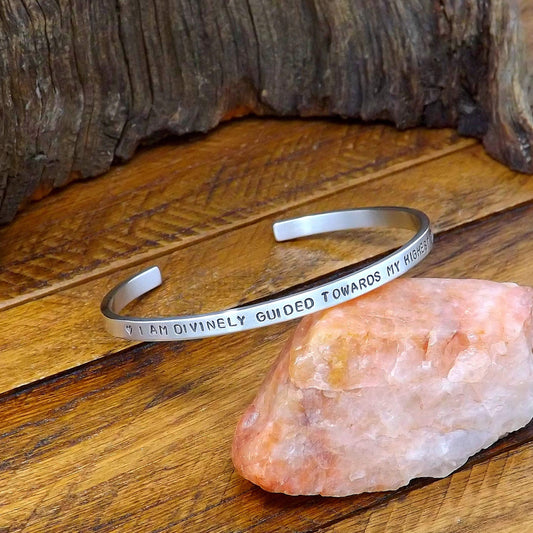 Left side view of a sterling silver affirmation cuff bracelet hand-stamped with "I Am Divinely Guided Towards My Highest Good".