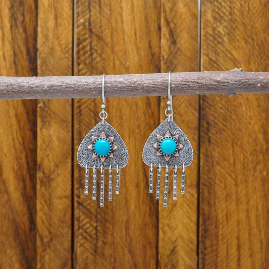 Hanging view of a pair of sterling silver dangle earrings with hubei turquoise gemstones and a copper sun design.