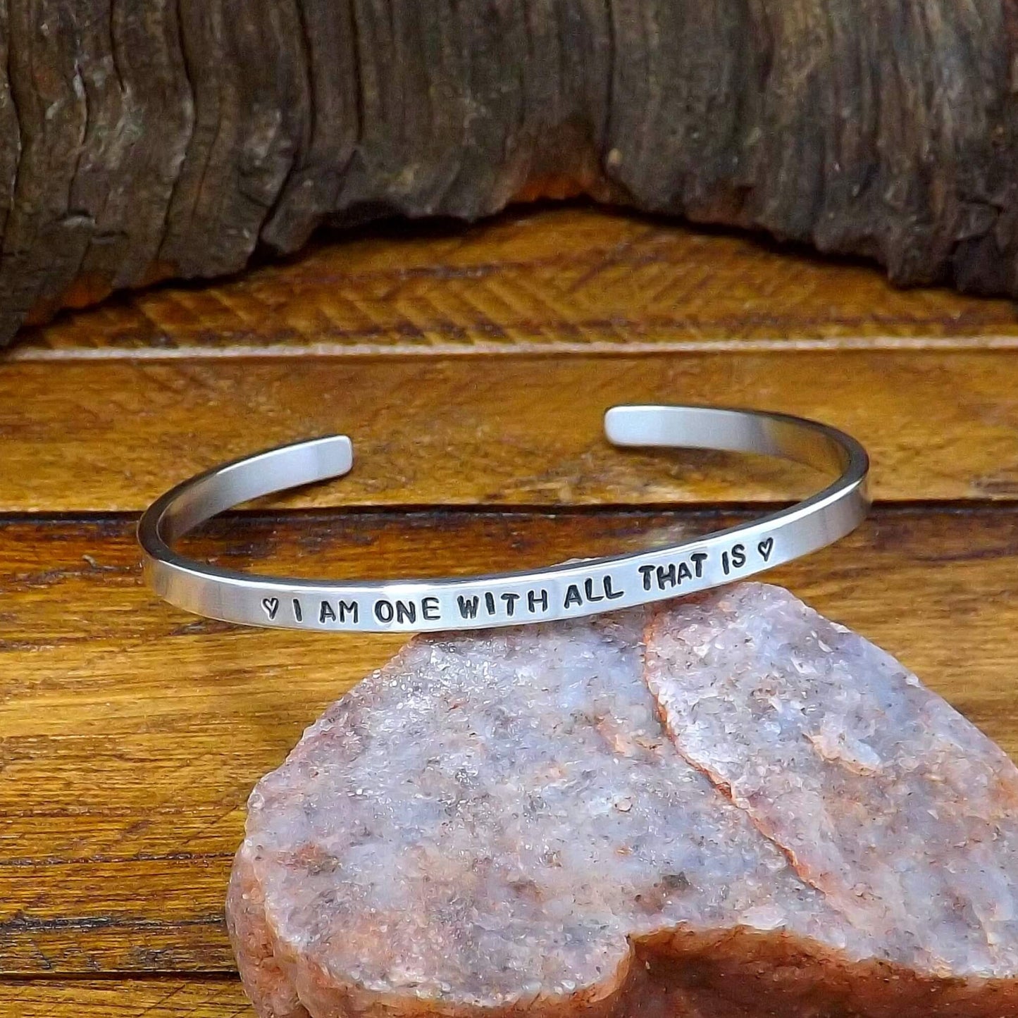 Front view of a sterling silver affirmation cuff bracelet hand-stamped with "I AM ONE WITH ALL THAT IS".