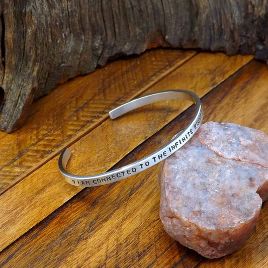 Left side view of a sterling silver affirmation cuff bracelet hand-stamped with "I AM CONNECTED TO THE INFINITE WISDOM OF THE UNIVERSE".