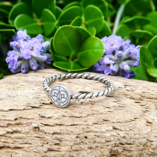 Right angle view of a sterling silver ring hand-stamped with Jenn's Zen Creations small logo.