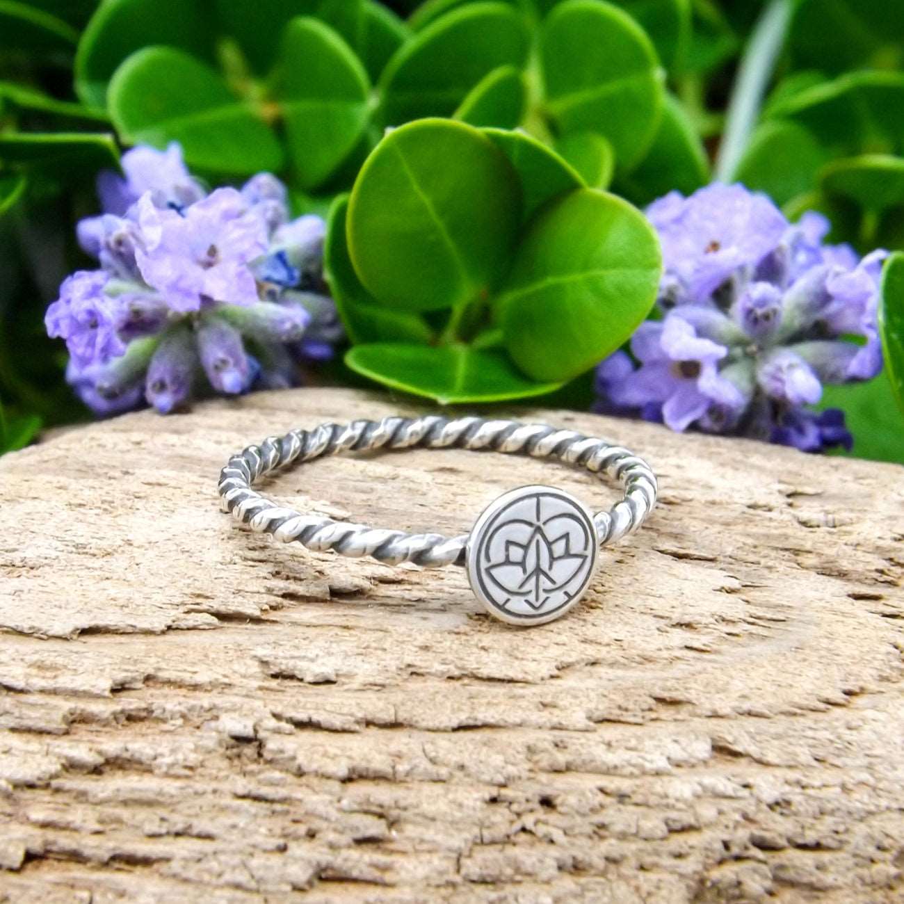 Left angle view of a sterling silver ring hand-stamped with Jenn's Zen Creations small logo.