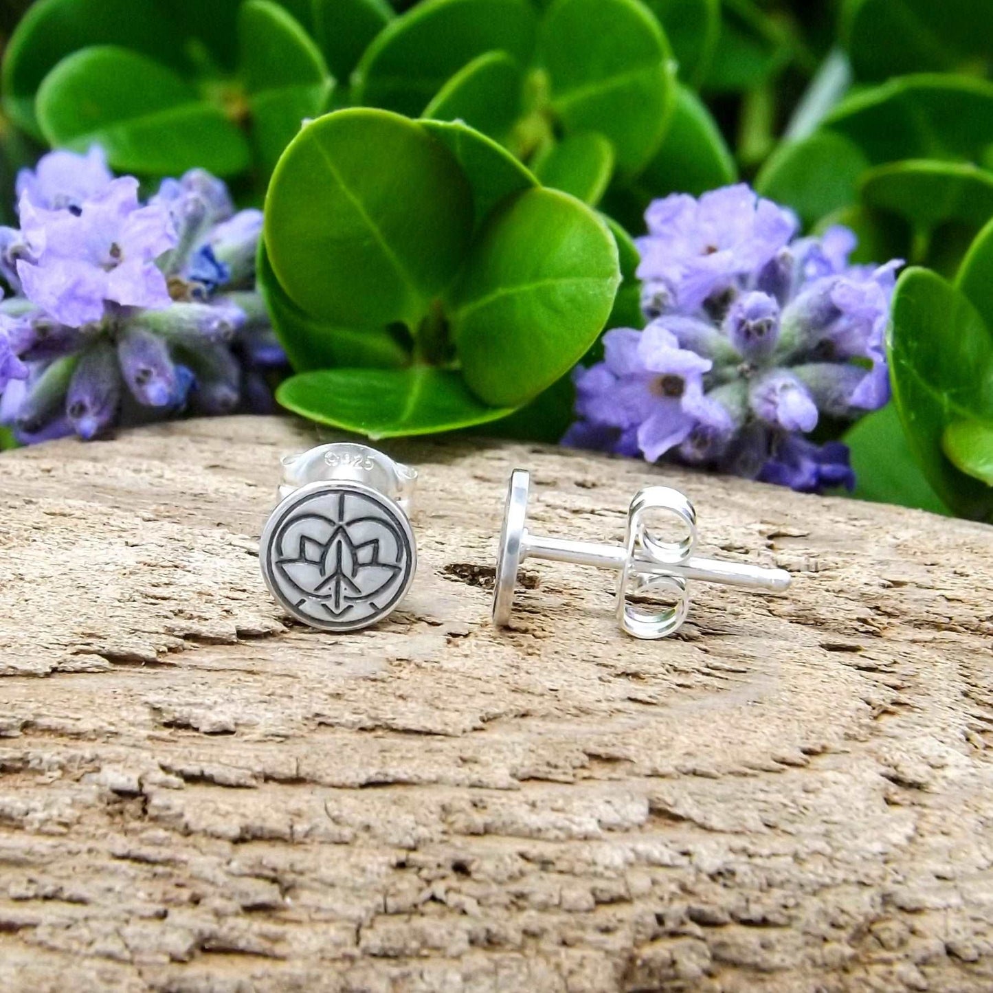 Side view of a pair of sterling silver stud earrings hand-stamped with small Jenn's Zen Creations logo.