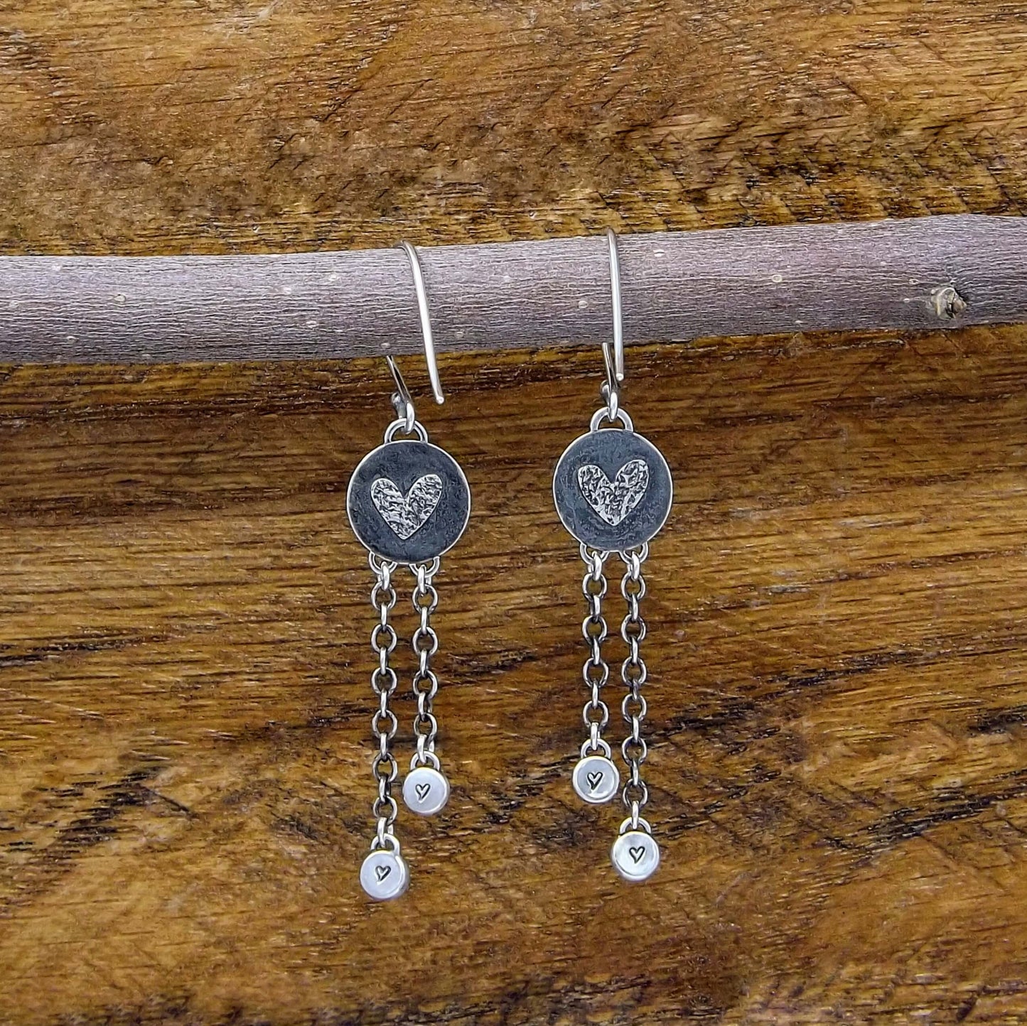 Back view of a pair of sterling silver dangle earrings with heart designs adorning the back.