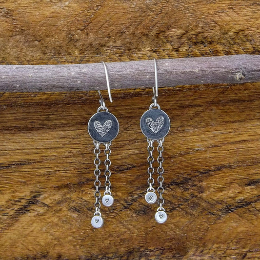 Back view of a pair of sterling silver dangle earrings with heart designs adorning the back.