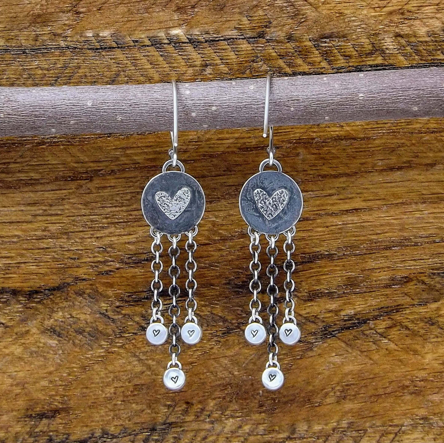 Back view of a pair of sterling silver dangle earrings with heart designs adorning the back.