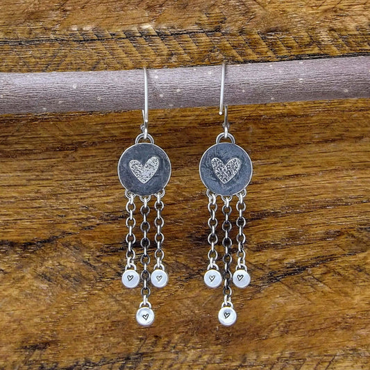 Back view of a pair of sterling silver dangle earrings with heart designs adorning the back.
