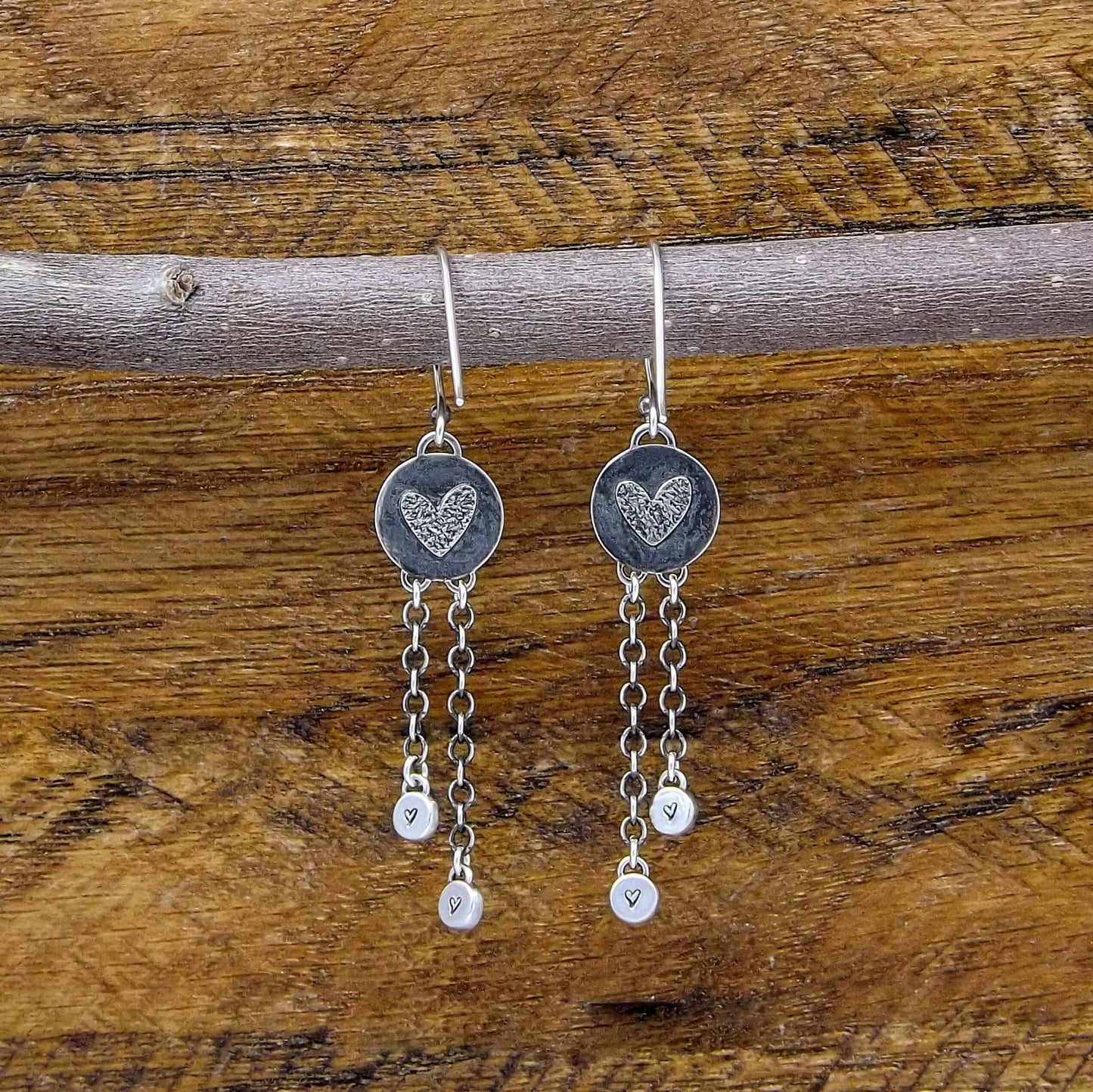 Back view of a pair of sterling silver dangle earrings with heart designs adorning the back.