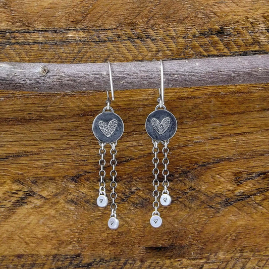Back view of a pair of sterling silver dangle earrings with heart designs adorning the back.