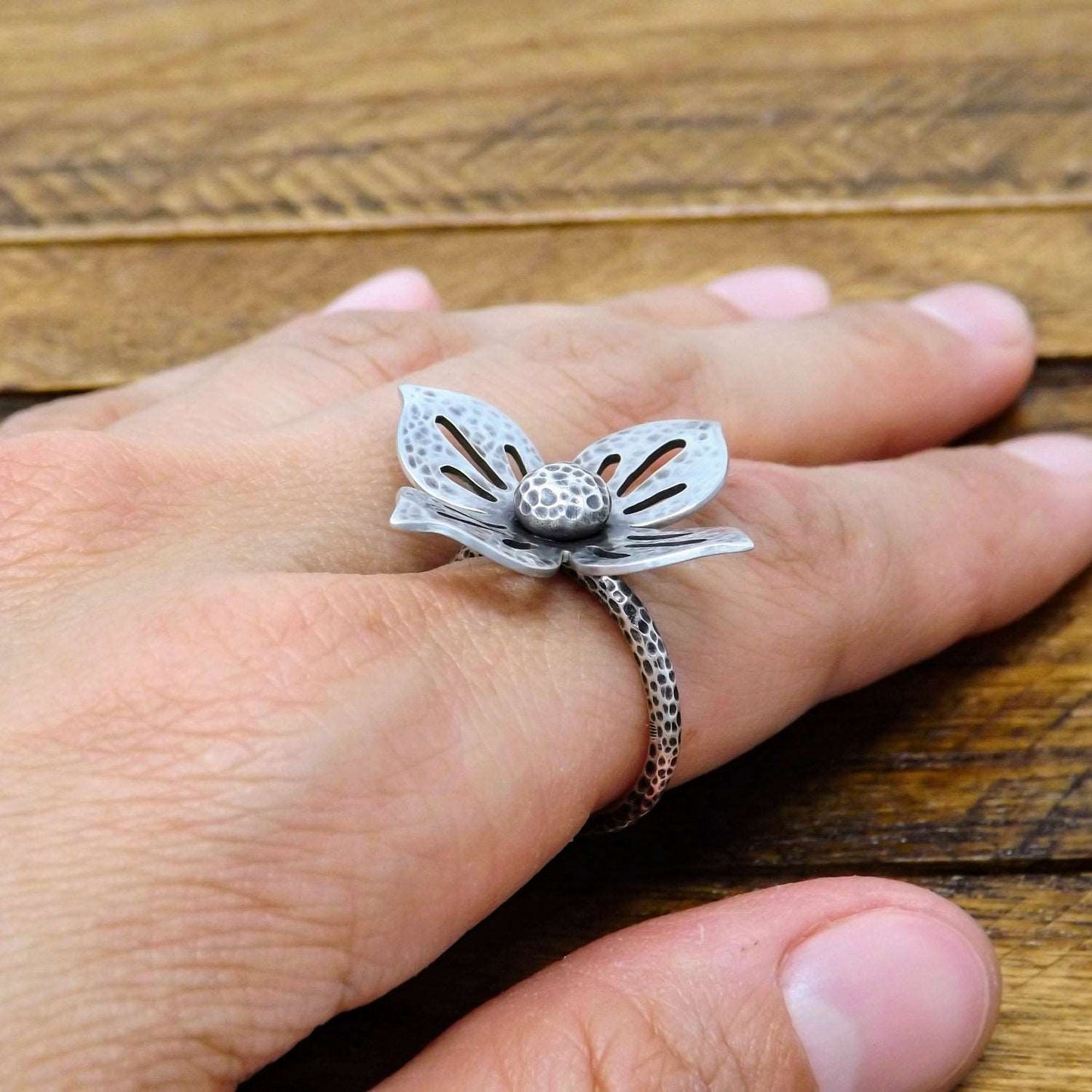 Secondary view of a one-of-a-kind argentium and sterling silver flower ring, worn on a finger.