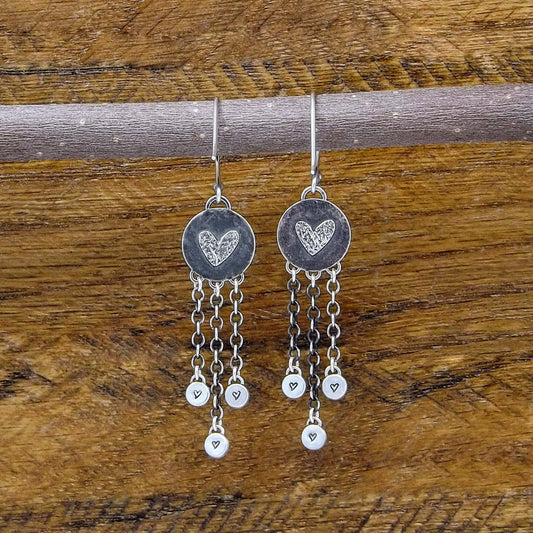 Back view of a pair of sterling silver dangle earrings with heart designs adorning the back.