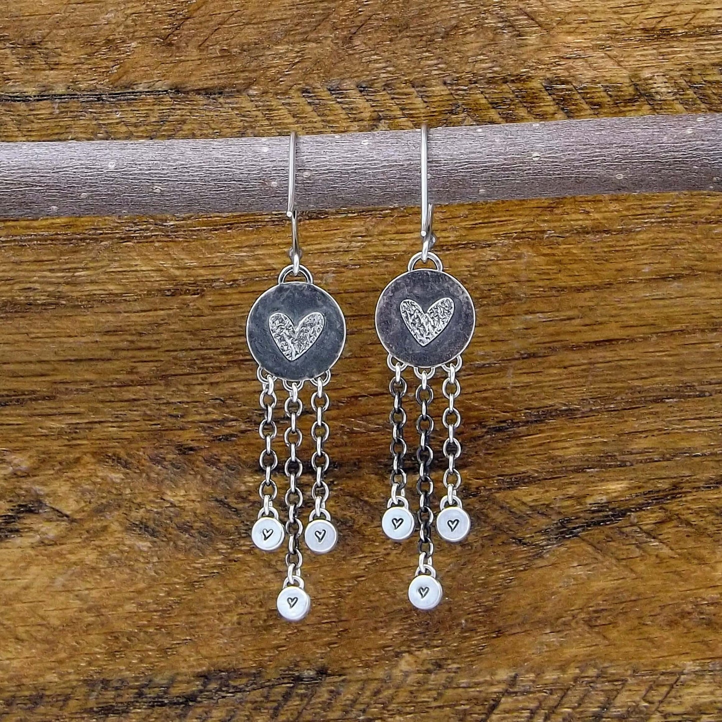 Back view of a pair of sterling silver dangle earrings with heart designs adorning the back.
