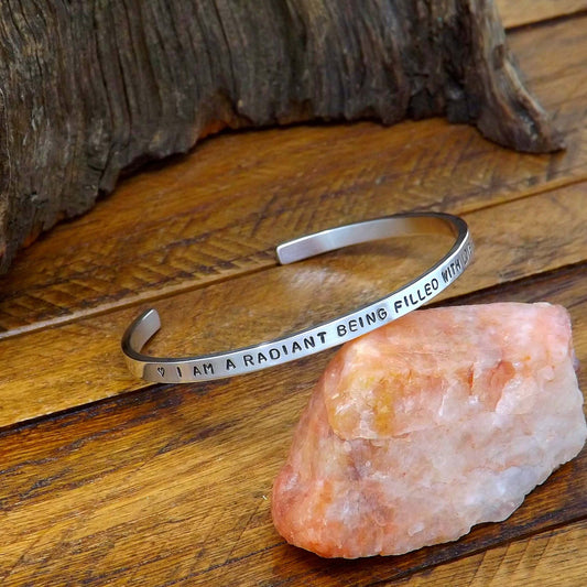 Left side view of a sterling silver affirmation cuff bracelet hand-stamped with "I AM A RADIANT BEING FILLED WITH LOVE & LIGHT".