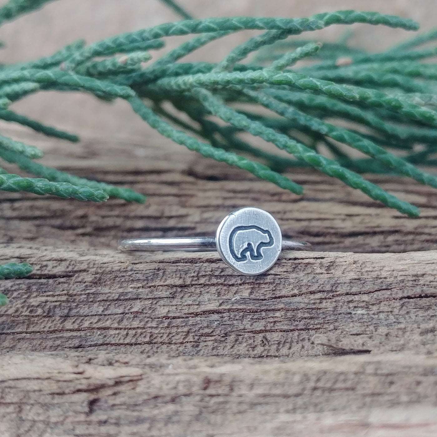 Left angle view of a sterling silver stacking ring hand-stamped with a baby bear design.