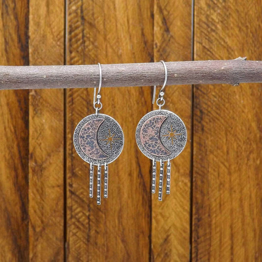 Hanging view of Front view of a pair of sterling silver dangle earrings adorned with a copper crescent moon and star.