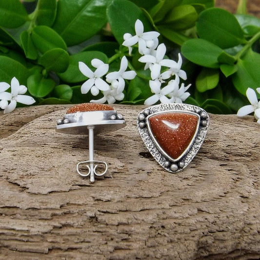 Side view of a pair of silver goldstone stud earrings.