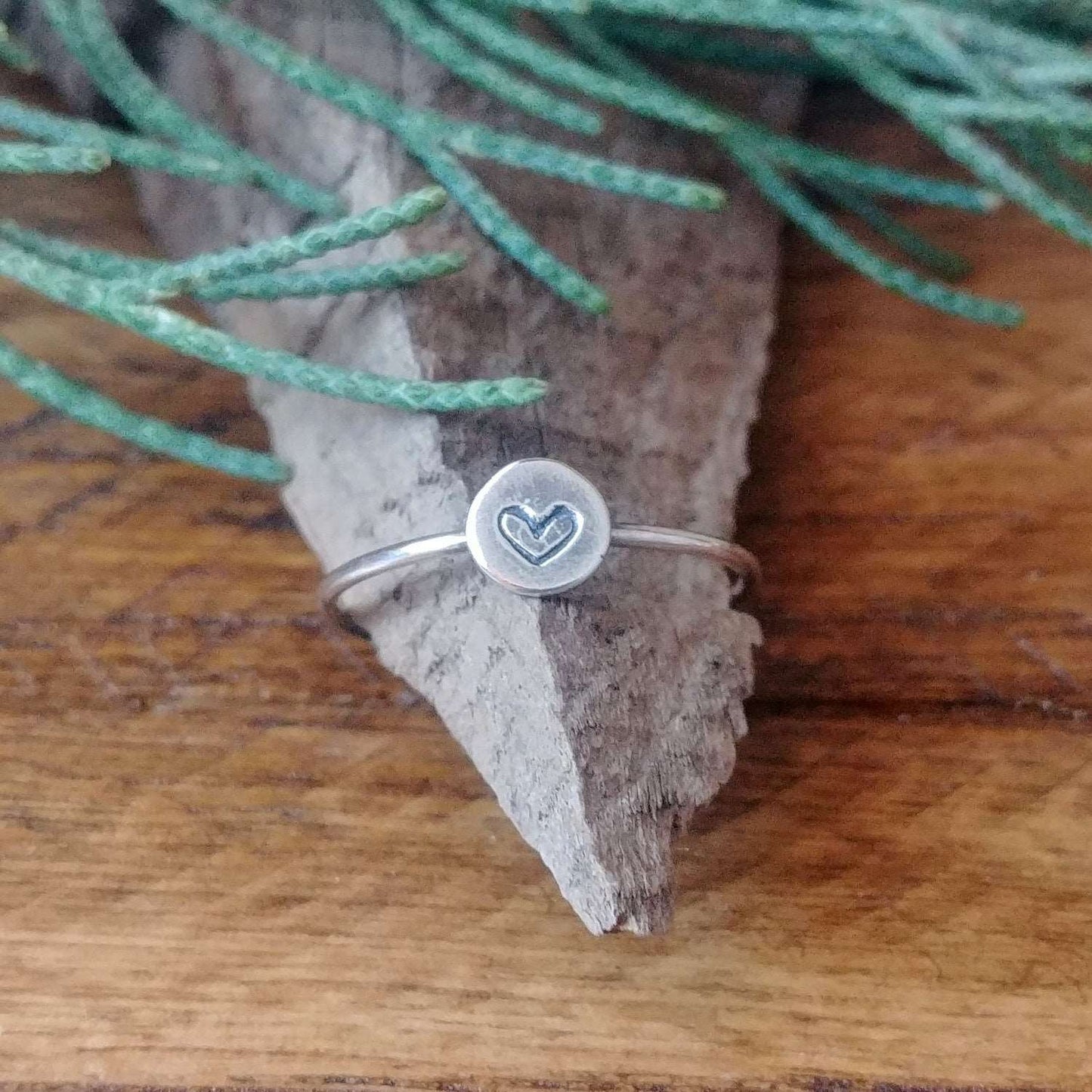 A sterling silver stacking ring with a hand-stamped tiny heart design.