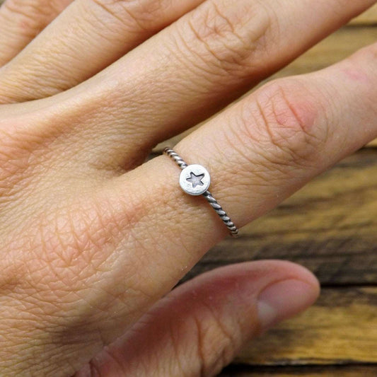 Sterling silver stacking ring hand-stamped with tiny star design, worn on a finger.