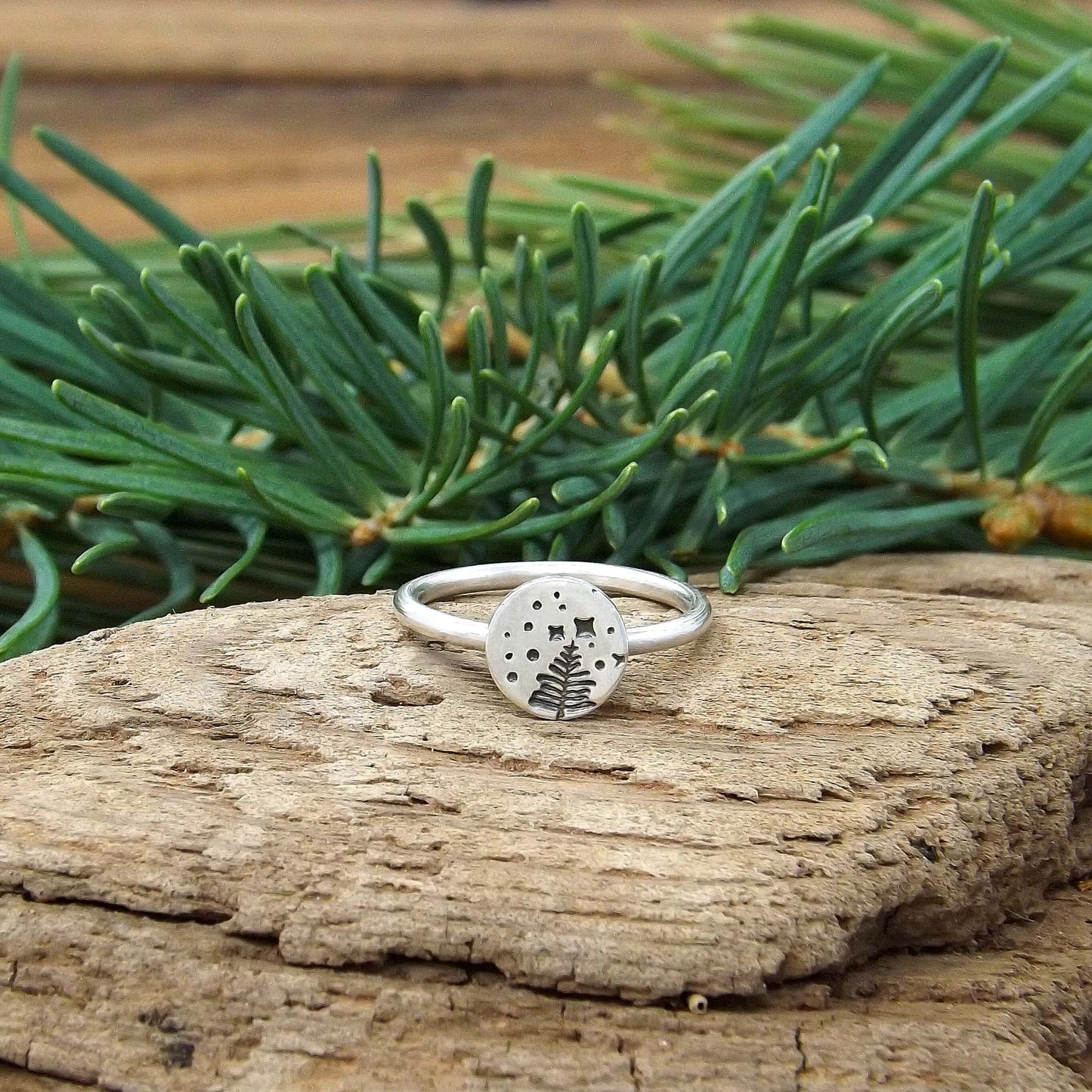 Front view of a sterling silver stacking ring with a hand-stamped starry night pine tree design.