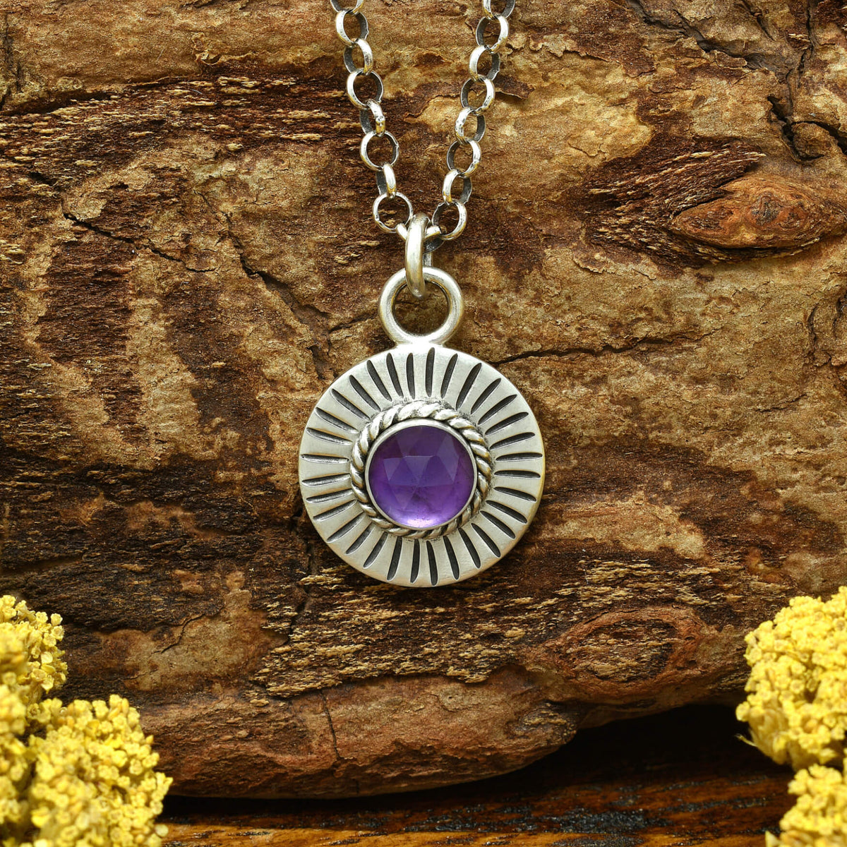 Front view of a sterling silver sunburst necklace with a rose cut faceted amethyst gemstone.