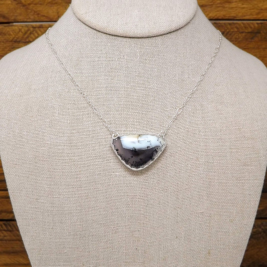 Display bust view of a sterling silver necklace with a dendritic opal gemstone and cut out butterfly design on the back.