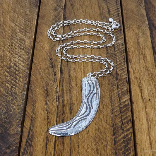 Full view of a sterling silver necklace with flowing organic curves and raised textured design made using chasing and repoussé technique.