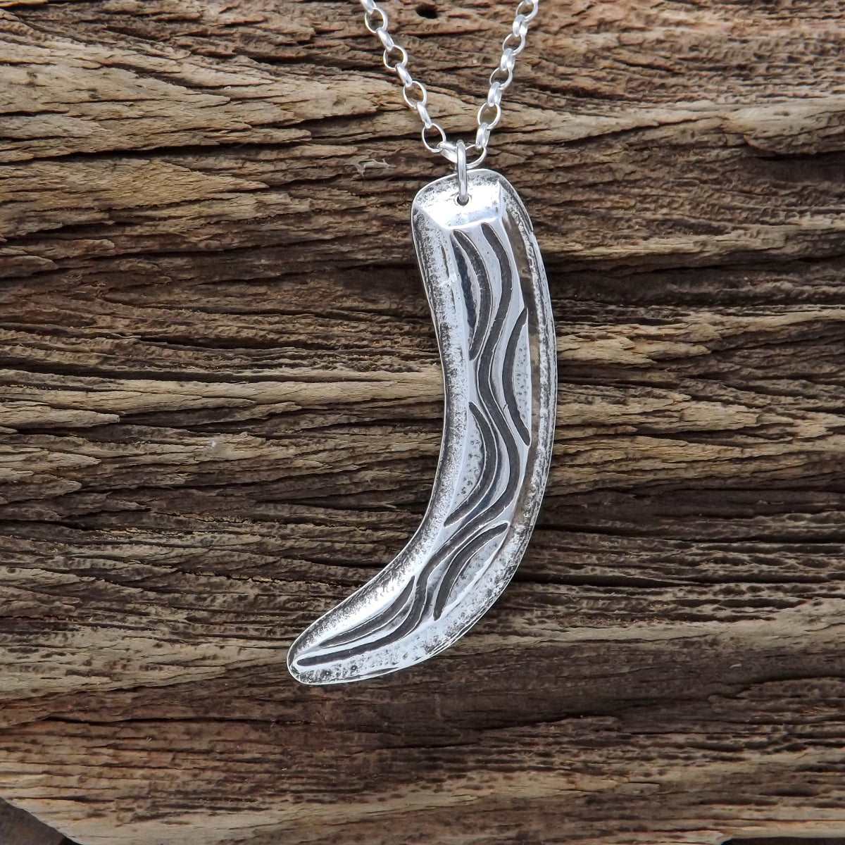 Front view of a sterling silver necklace with flowing organic curves and raised textured design made using chasing and repoussé technique.