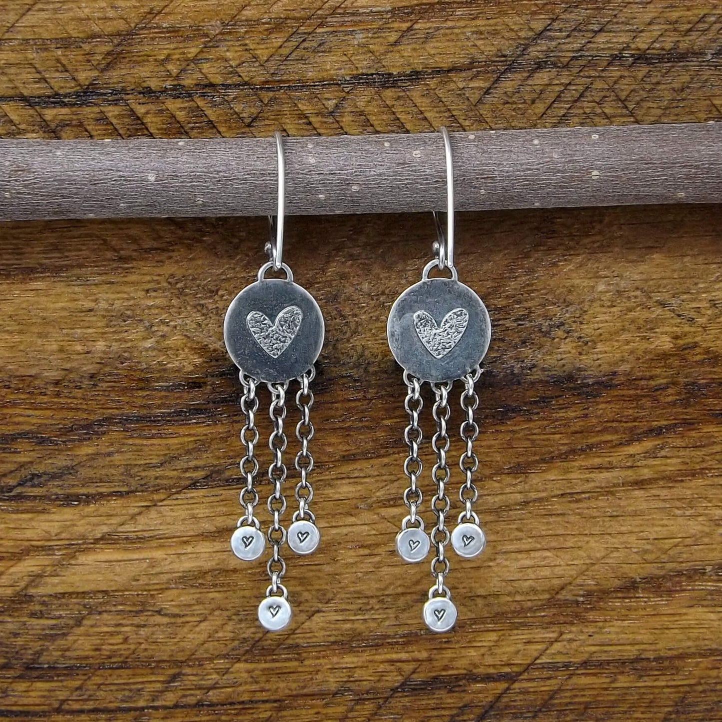 Back view of a pair of sterling silver dangle earrings with heart designs adorning the back.