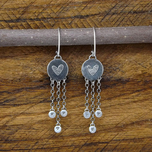 Back view of a pair of sterling silver dangle earrings with heart designs adorning the back.