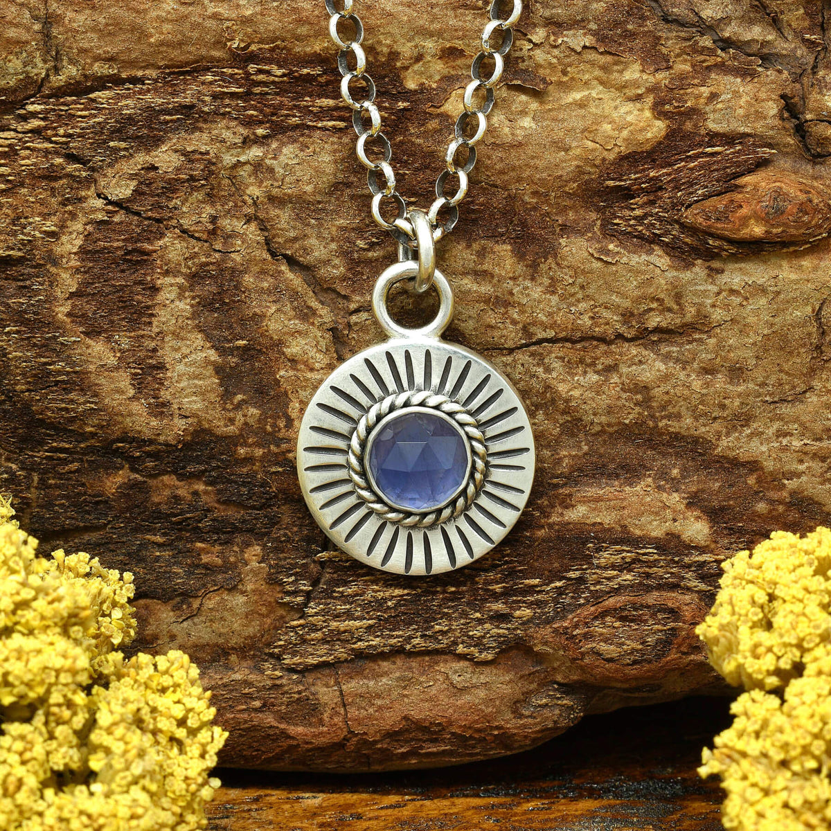 Front view of a sterling silver sunburst necklace with a rose cut faceted iolite gemstone.