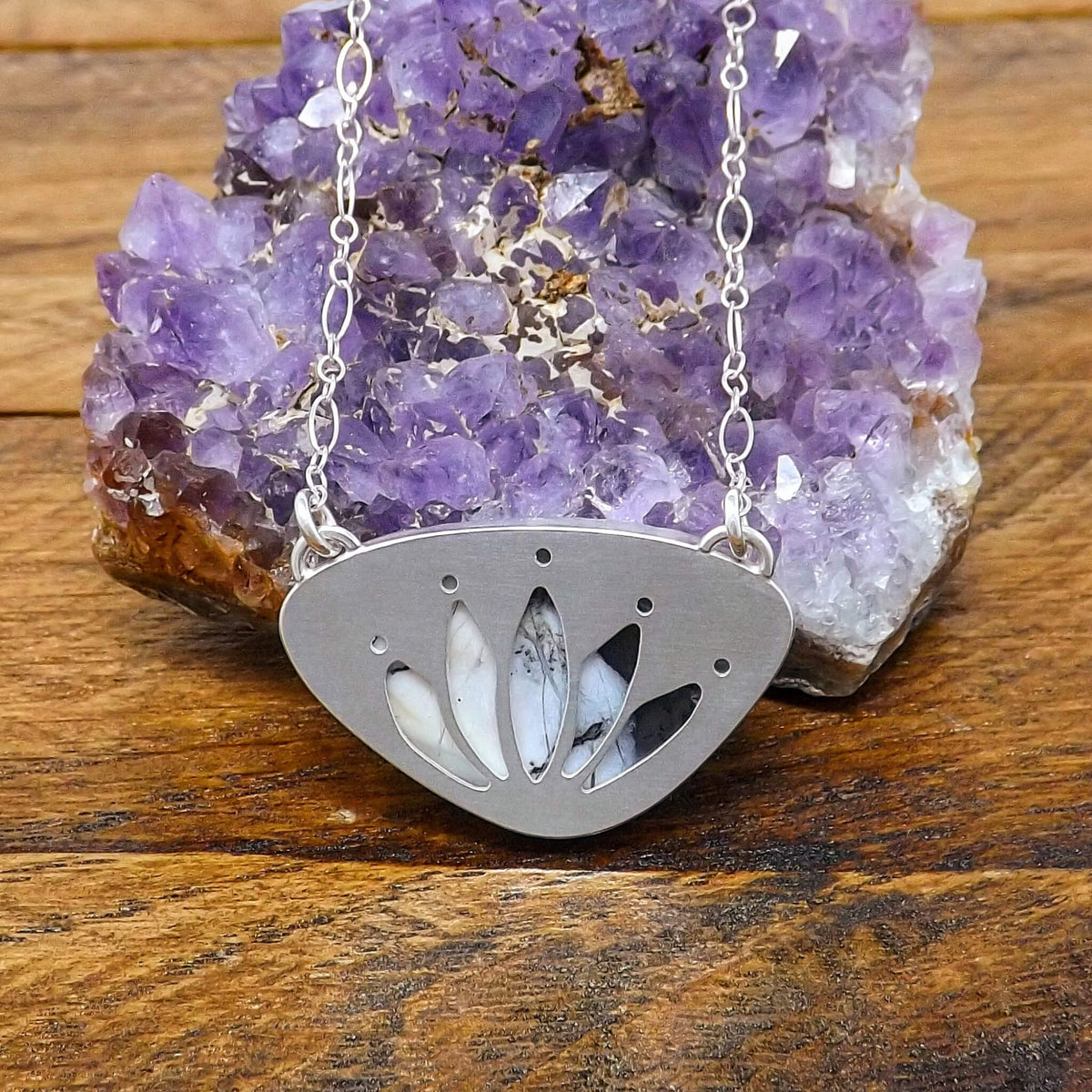 Back view of a sterling silver necklace with a cut out lotus flower design and dendritic opal gemstone.