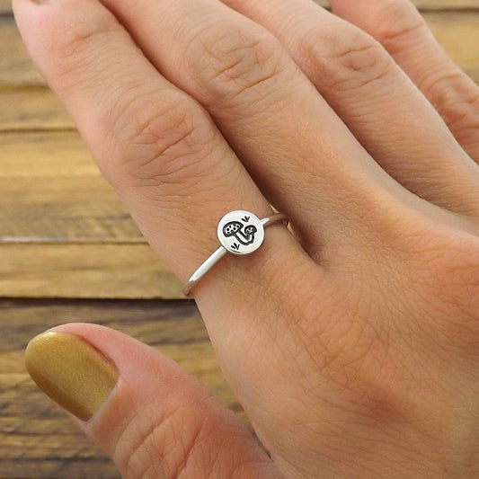 Sterling silver stacking ring hand-stamped with mushroom design, worn on a finger.