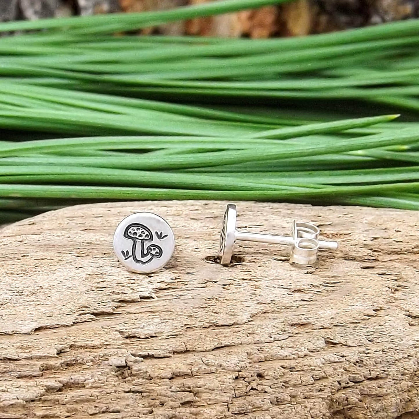 Side view of a pair of sterling silver hand-stamped mushroom stud earrings.