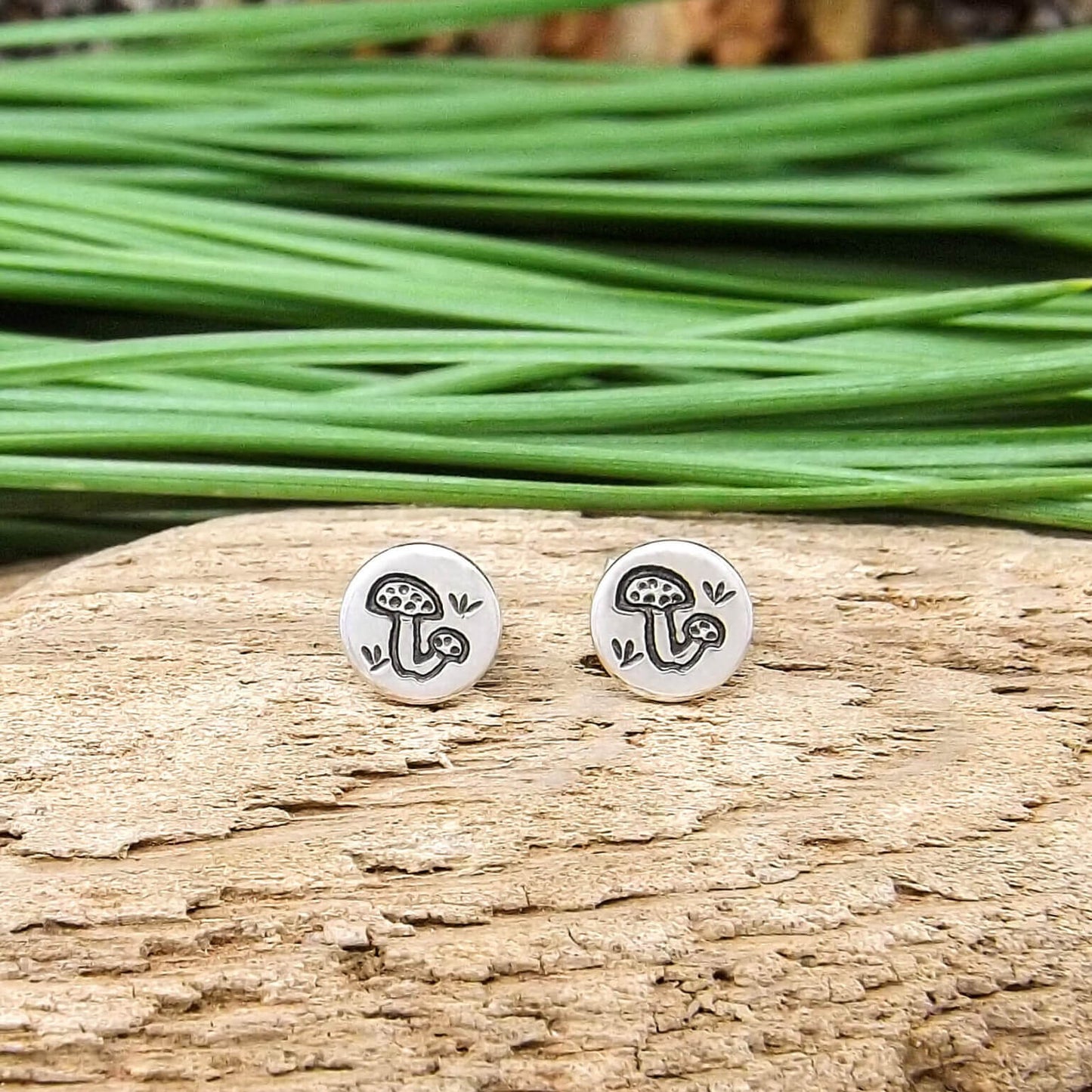 A pair of sterling silver stud earrings hand-stamped with mushroom design.