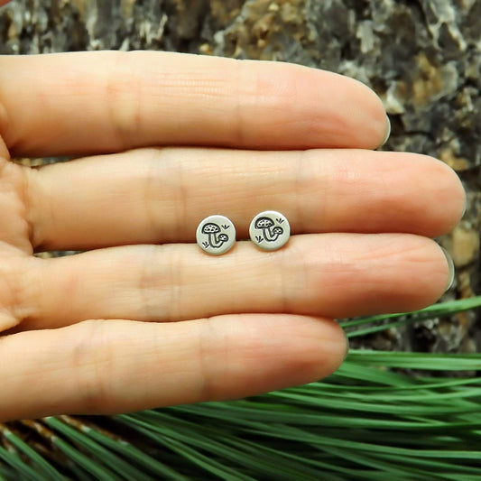 Size reference view of a pair of sterling silver hand-stamped mushroom stud earrings.