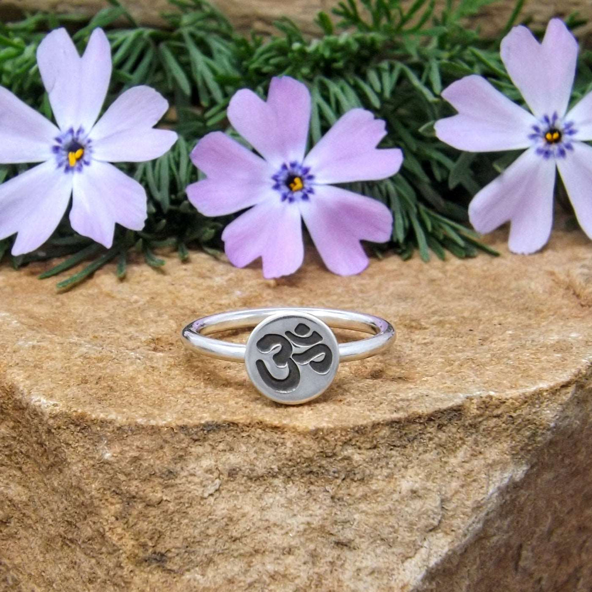 A sterling silver stacking ring with a hand-stamped om symbol design.