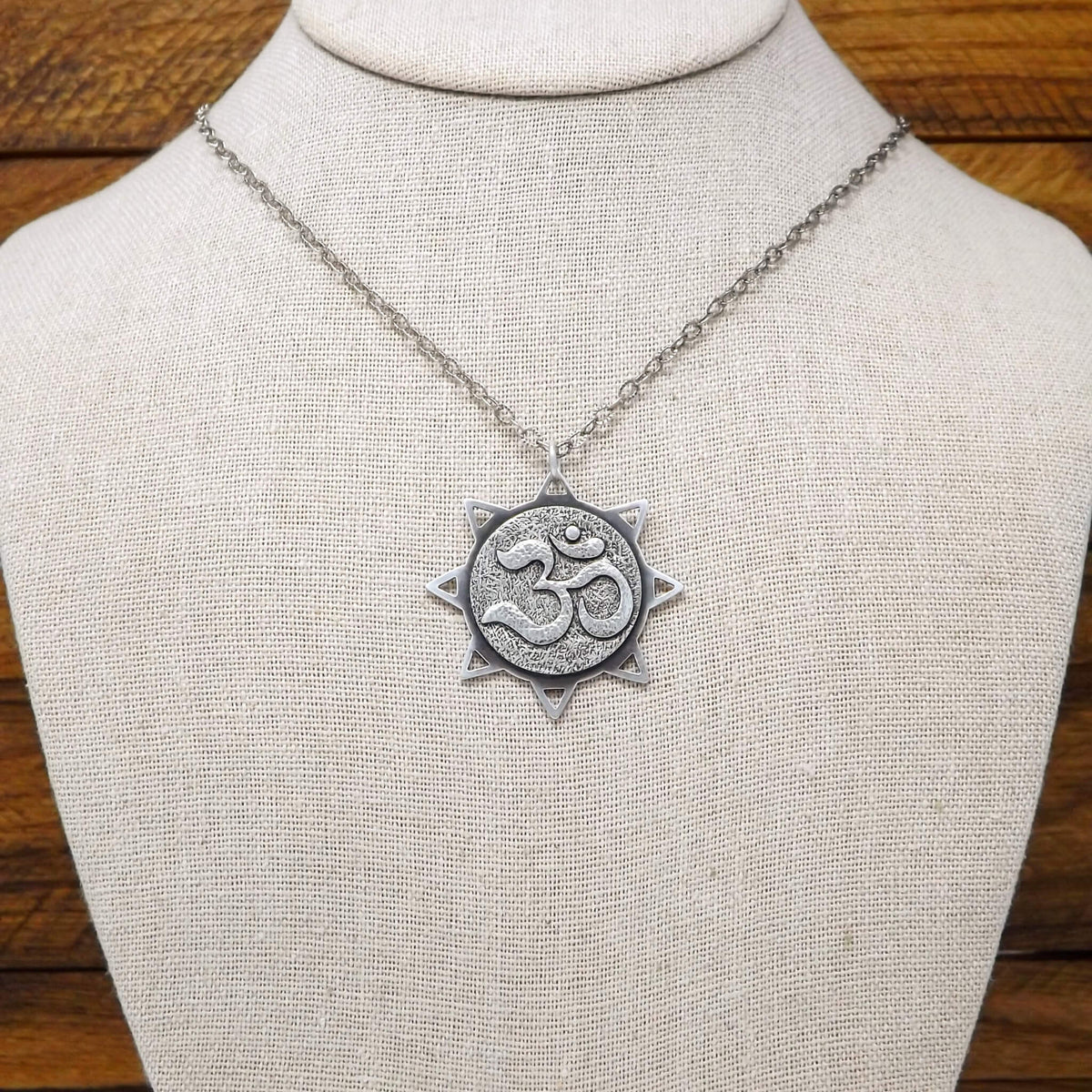 Display bust view of a sterling silver sun necklace with an om symbol in the center.