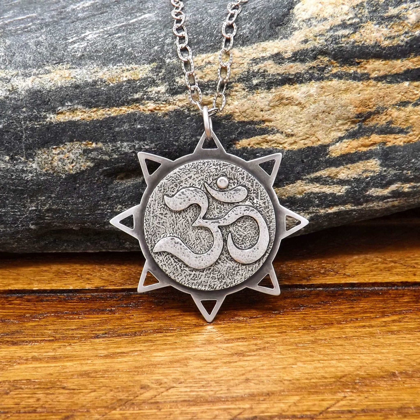 Front view of a sterling silver sun necklace with an om symbol in the center.