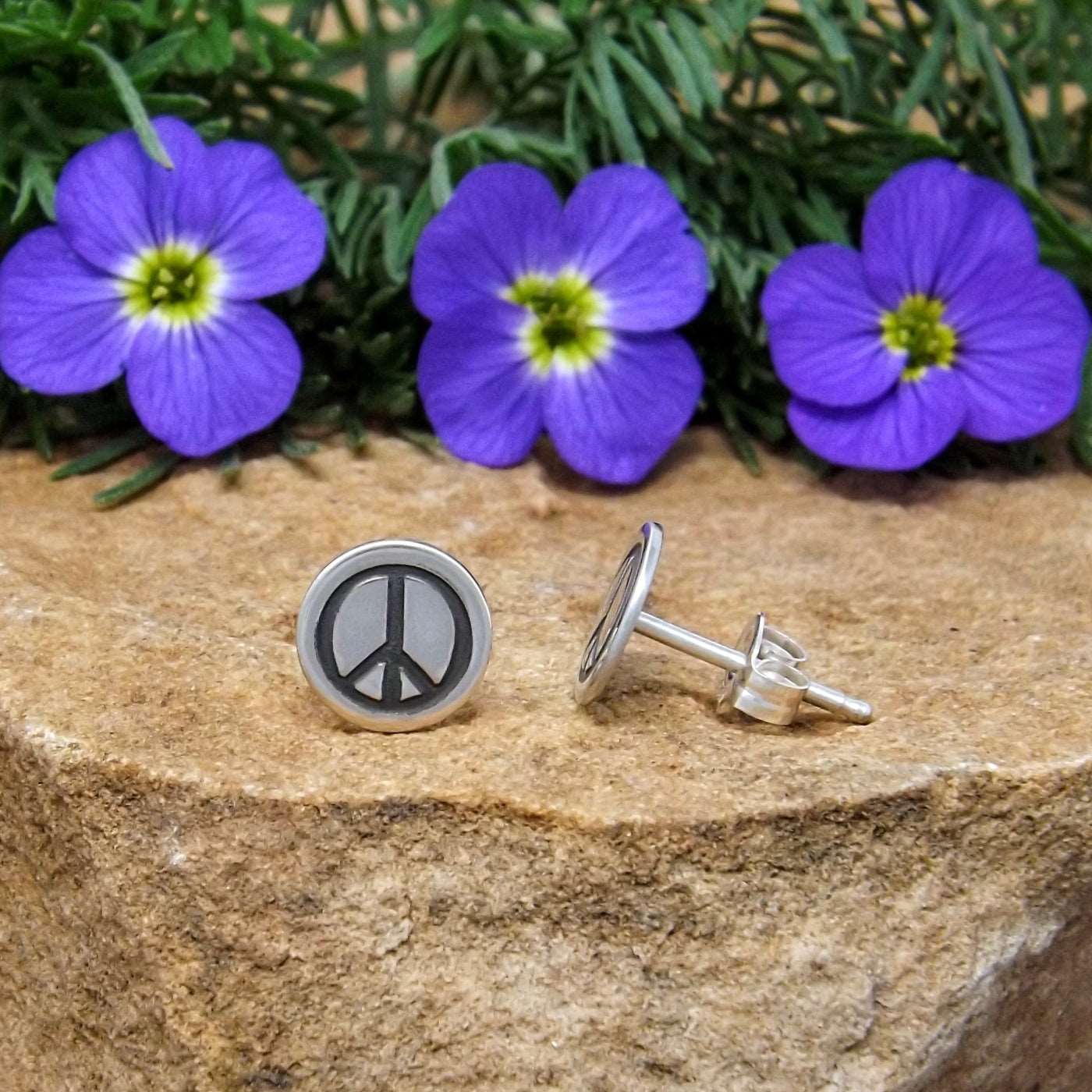 Side view of sterling silver stud earrings hand-stamped with peace sign design.
