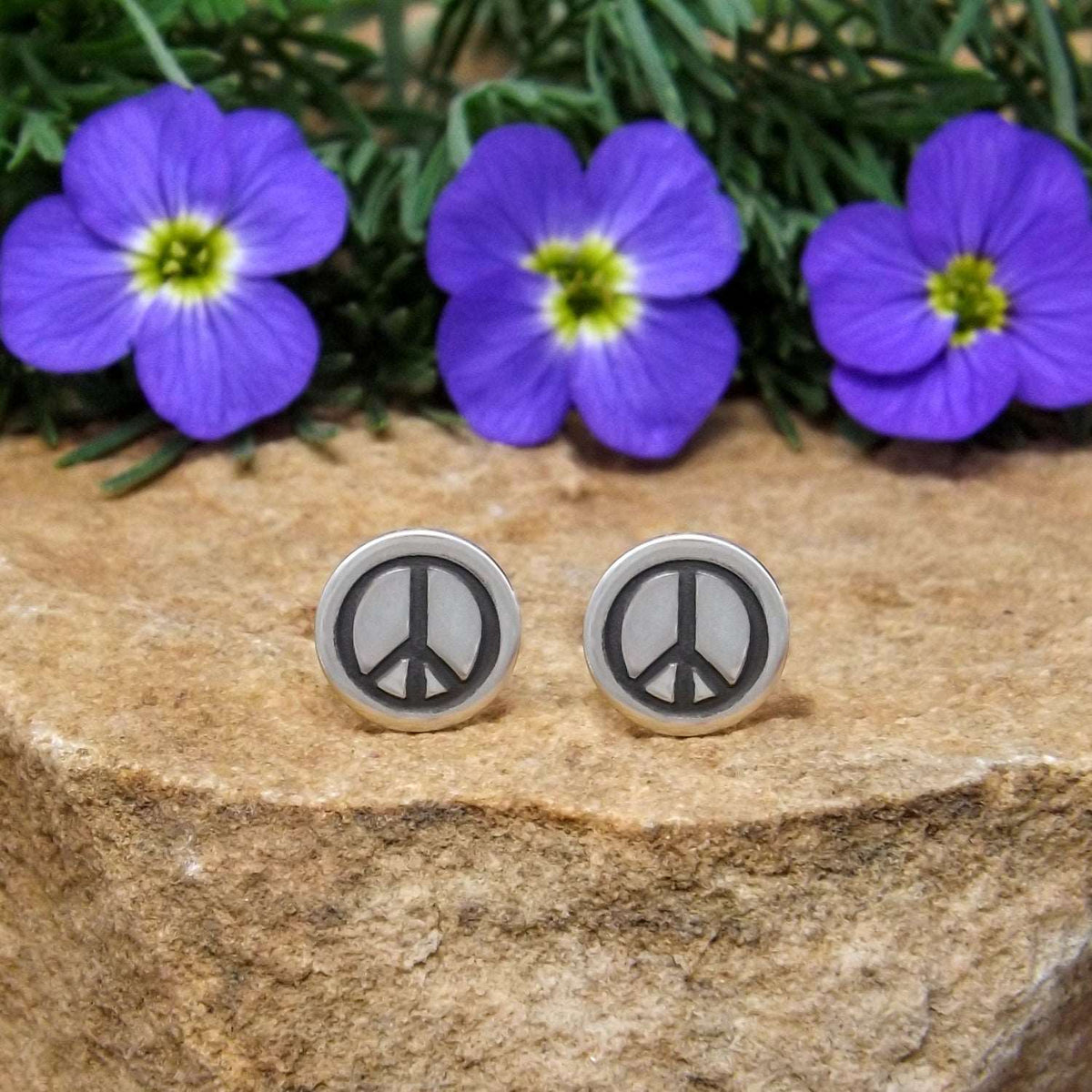 Front view of sterling silver stud earrings hand-stamped with peace sign design.