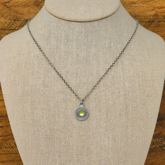 Bust view of a sterling silver sunburst necklace with a rose cut faceted peridot gemstone.