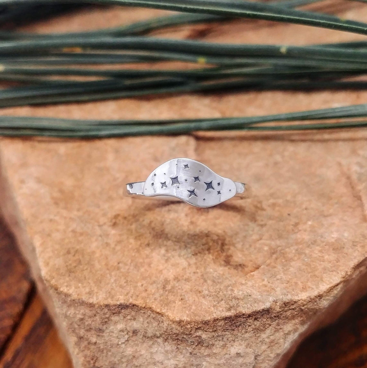 Front view of a sterling silver ring hand-stamped with a star cluster design.