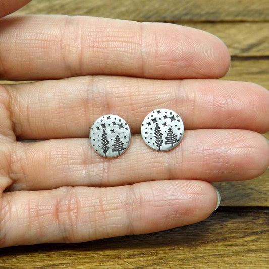 Size reference photo of a pair of sterling silver earrings hand-stamped with a starry night forest design.